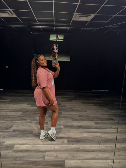 Person taking a mirror selfie in a room with dark walls and wooden floor.